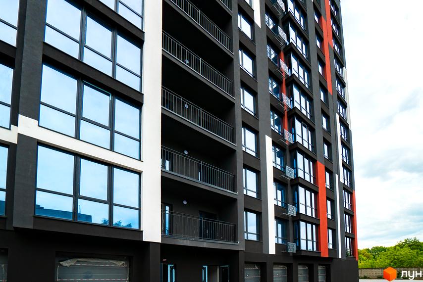 Висотна будівля ЖК U One з панорамними вікнами та балконами. Фасад будинку виконаний в темних тонах з яскравими акцентами.