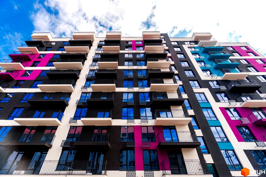Фасад багатоповерхового будинку Житлового комплексу Family Plaza з балконами та яскравими кольоровими вставками. Вид знизу, видно частину неба.