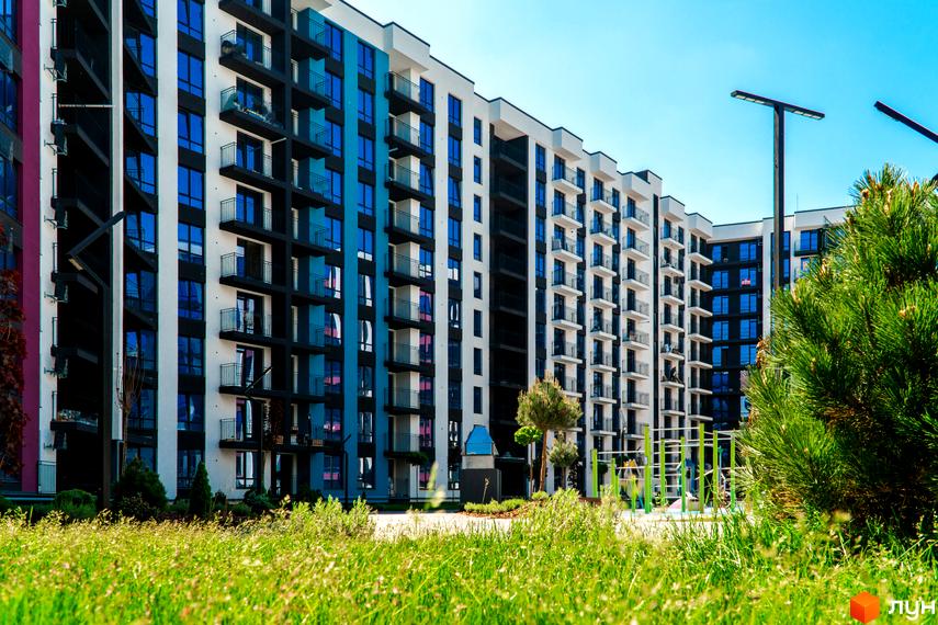 Зображення фасаду та прибудинкової території Житлового комплексу Family Plaza. Багатоповерховий будинок з балконами та озелененням.