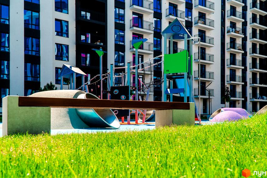 Зображення дитячого майданчика біля багатоповерхового будинку в Житловому комплексі Family Plaza. Вигляд фасаду будинку та прибудинкової території.