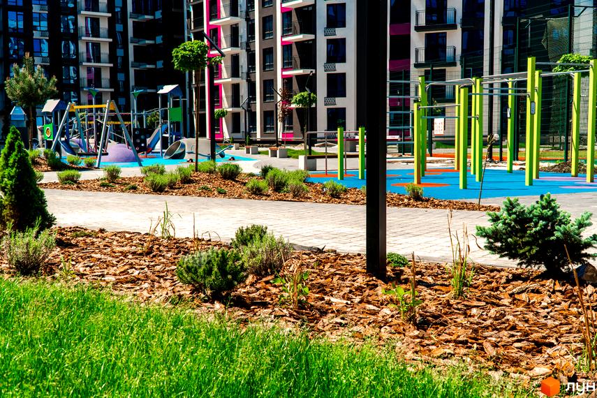 Зображення дитячого майданчика біля Житлового комплексу Family Plaza. На фоні багатоповерховий будинок з балконами.