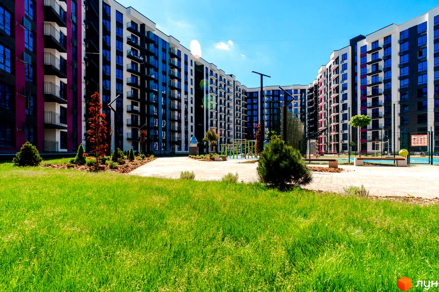 Зовнішній вигляд Житлового комплексу Family Plaza з яскравими фасадами та великими вікнами. У дворі зелений газон та ландшафтний дизайн.