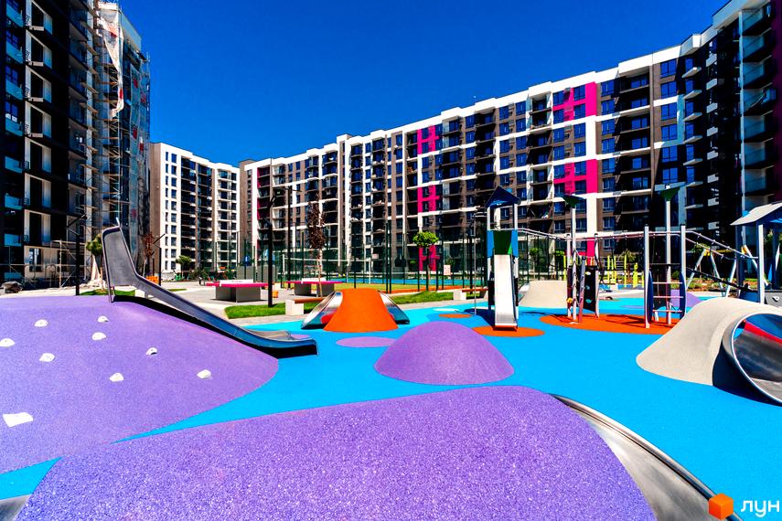 Зображення Житлового комплексу Family Plaza з кольоровим дитячим майданчиком на фоні багатоповерхового будинку.