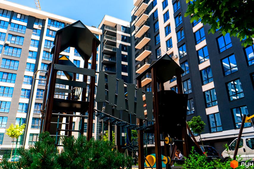 Житловий комплекс Comfort Park з дитячим майданчиком. Сучасні будівлі з панорамними вікнами та балконами.