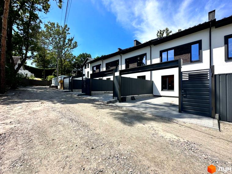 Зображення сторінки житлового комплексу Таунхауси Т-35. Білі будинки з темними вікнами та парканами, перед будинками – гравійне покриття.