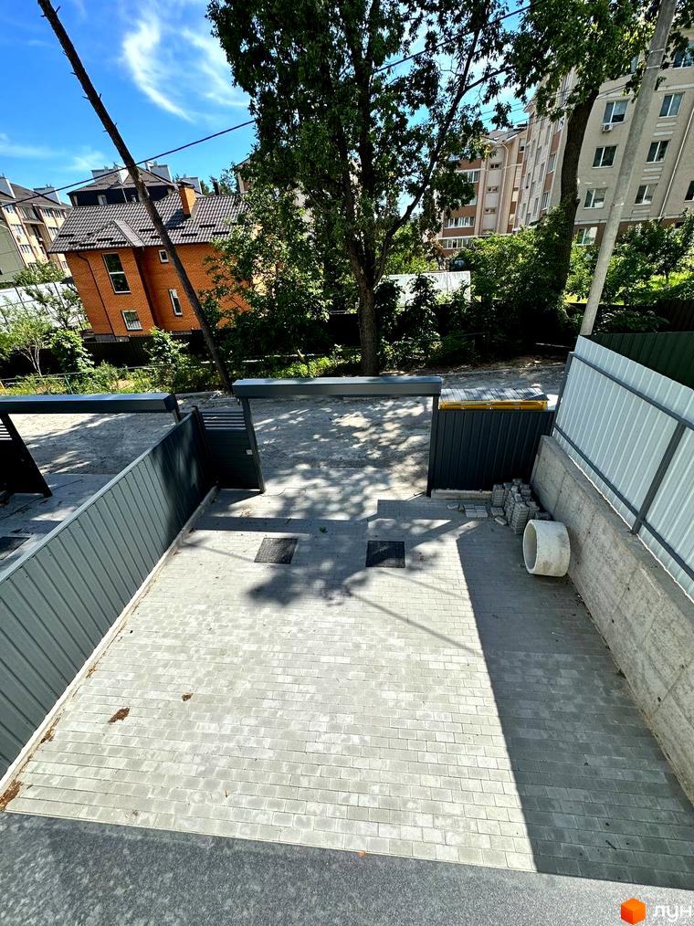 Вигляд на таунхауси Т-35 з двором, вимощеним бруківкою. На задньому плані видно зелені дерева та сусідні будинки.