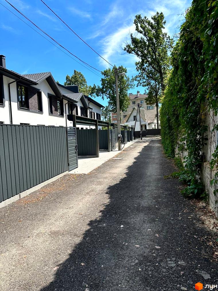 Таунхаус Т-37: фасади будинків з темним дахом та великими вікнами, сірий паркан та доглянута прибудинкова територія.