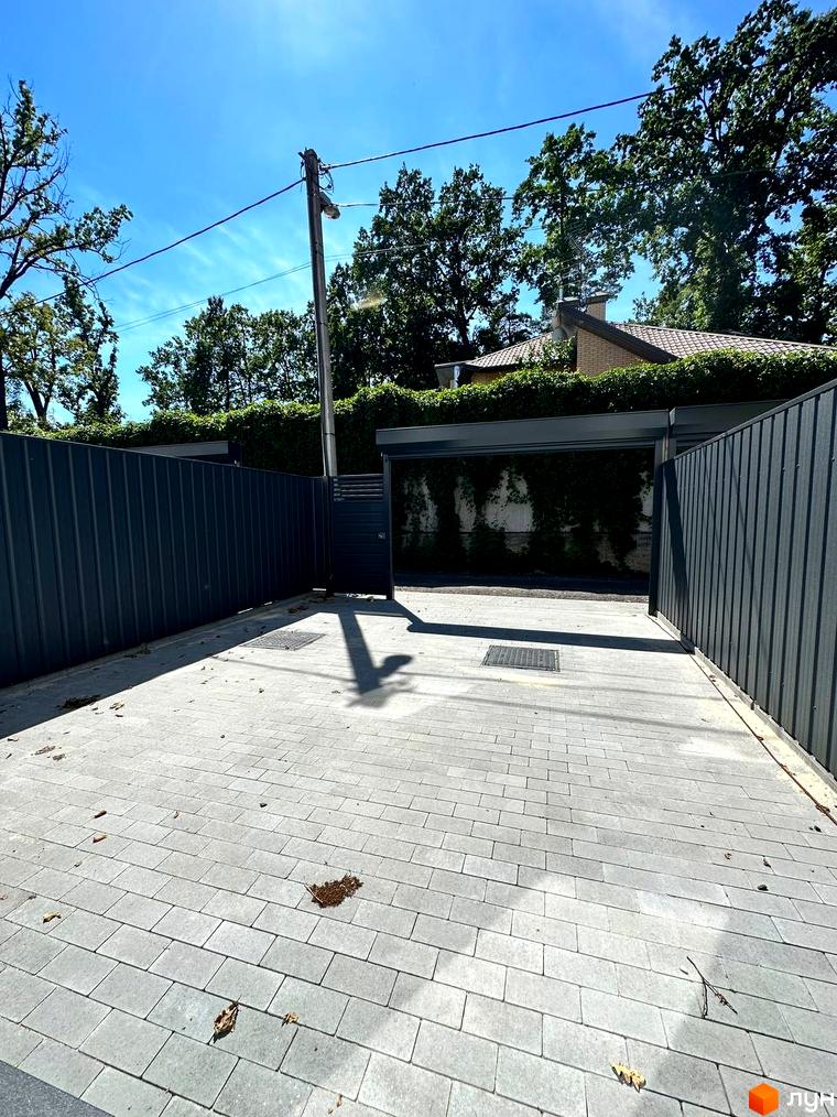 Таунхаус Т-37: сучасний фасад та вимощена бруківкою прибудинкова територія з парканом.