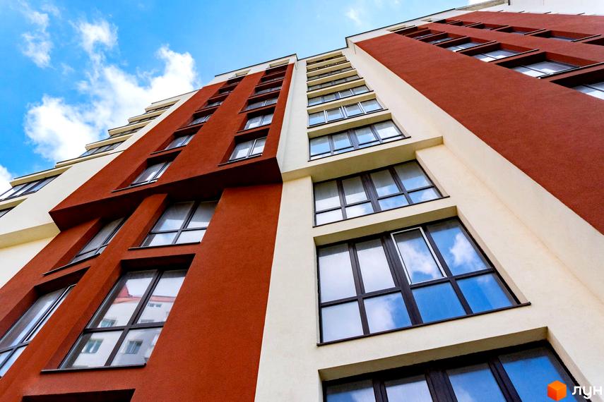 Фасад житлового комплексу Comfort House з панорамними вікнами та балконами. Зовнішній вигляд будівлі у світлих та теракотових тонах.