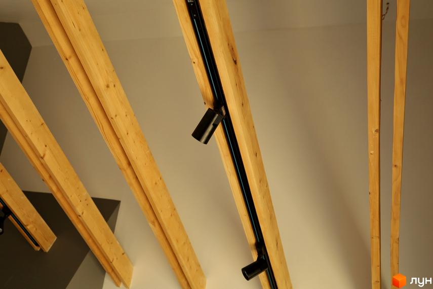 Інтер'єр житлового комплексу AMA FAMILY RESORT з дерев'яними балками та трековими світильниками. Сучасний дизайн стелі для комфортного проживання.