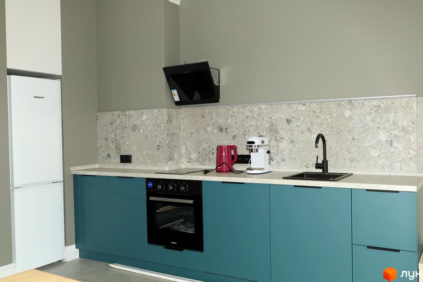Сучасна кухня з білим холодильником Liebherr, вбудованою технікою та бірюзовими фасадами. Стильний дизайн інтер'єру.