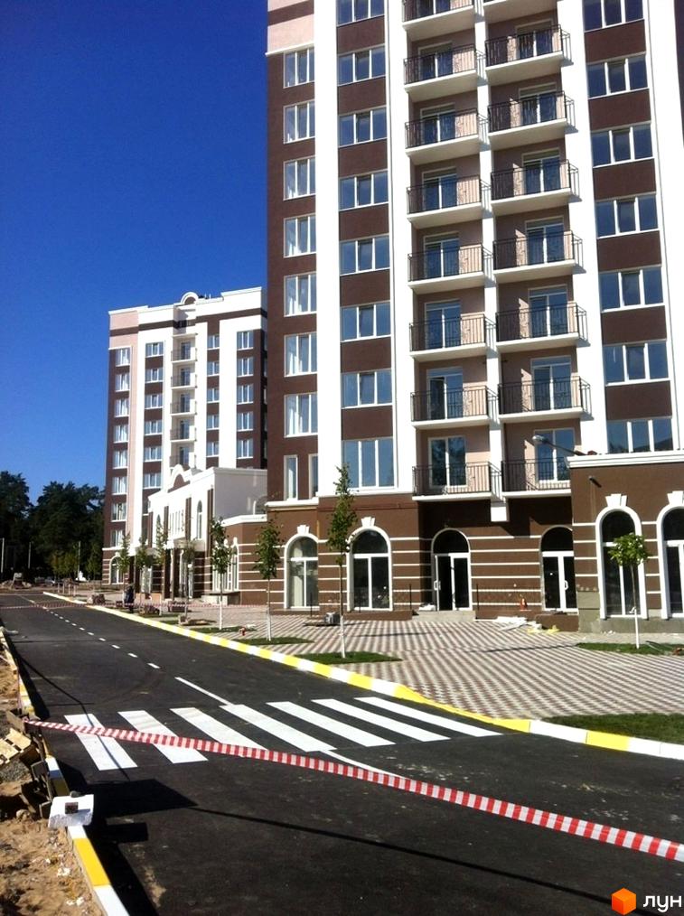 Житловий комплекс Центральний: багатоповерхові будівлі з балконами та вікнами. Перед ними дорога з пішохідним переходом, огородженим стрічкою.