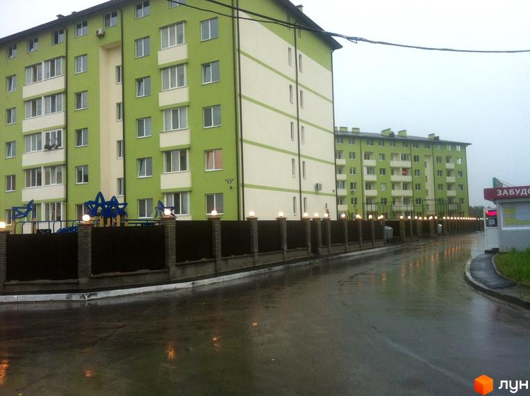 Житловий комплекс Смарагдове місто в Нових Петрівцях. Зелені фасади будинків з білими смугами, огороджена територія з ліхтарями.
