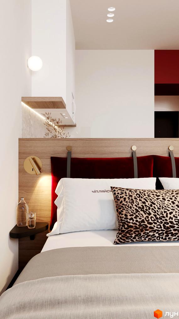 Інтер'єр спальні в апарт-готелі. Ліжко з подушками та приліжковим столиком з лампою.