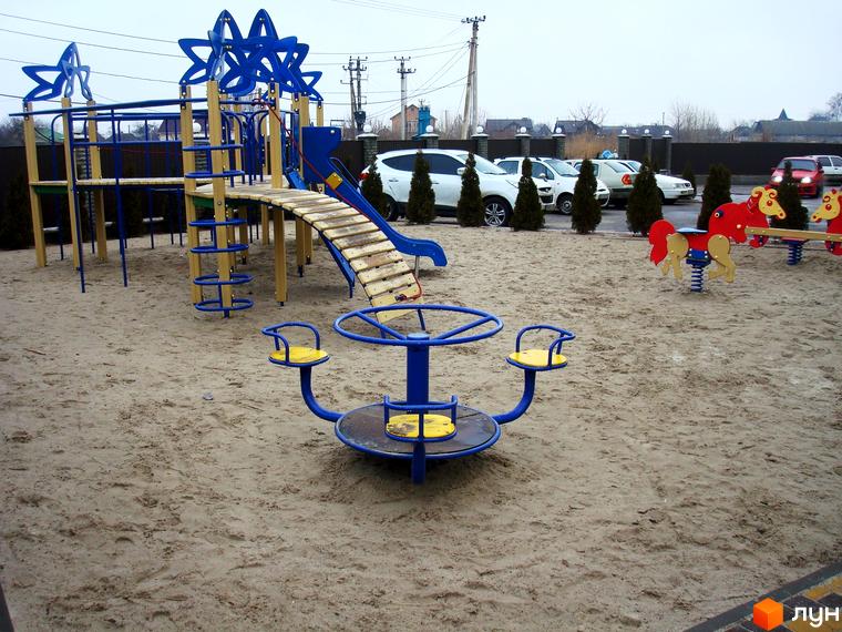 Дитячий майданчик з гойдалками, каруселлю та гіркою на піщаному покритті. ЖК Смарагдове місто (Нові Петрівці) – це сучасний житловий комплекс з розвиненою інфраструктурою.