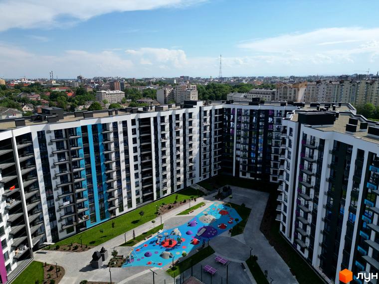 Зображення фасаду та подвір'я Житлового комплексу Family Plaza. Вигляд багатоповерхового будинку з дитячим майданчиком.