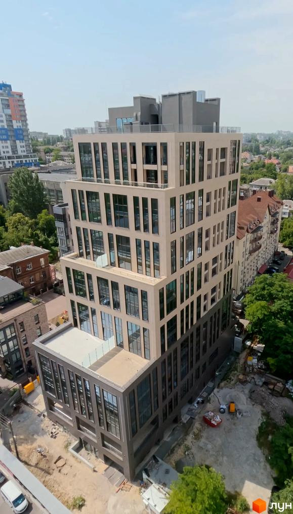 Житловий комплекс DeLight Hall з багатоповерховою будівлею та вікнами, що виходять на вулицю. Навколо будівництва видно будівельні матеріали та дерева.