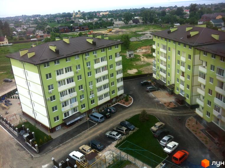 Зовнішній вигляд зелених багатоповерхових будинків ЖК Смарагдове місто (Нові Петрівці) з прибудинковою територією та парковкою. Фото новобудови з висоти пташиного польоту.