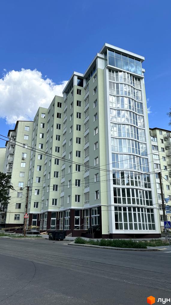 Зовнішній вигляд житлового комплексу Потьомкінський із світло-зеленими фасадами та великими вікнами. Навколо будинку видно дорогу та зелені насадження.