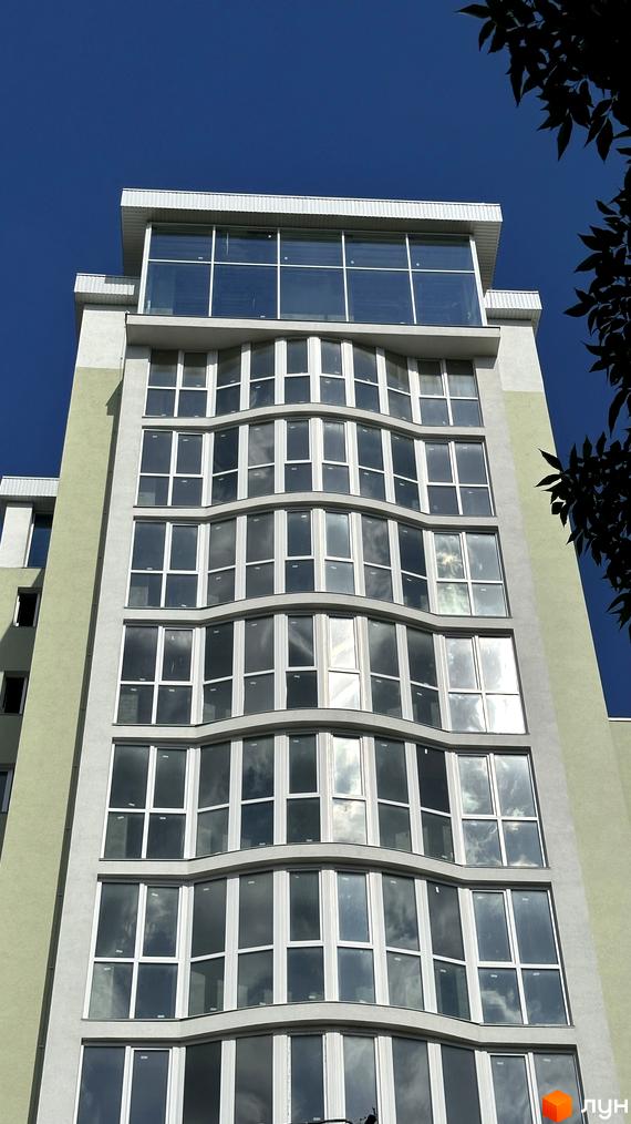 Зовнішній вигляд новобудови ЖК Потьомкінський з панорамними вікнами та хвилястими фасадами. Висотна будівля під блакитним небом.