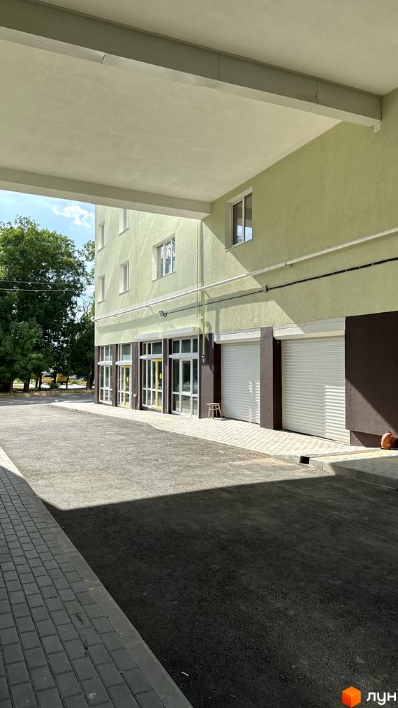 Житловий комплекс Потьомкінський має світло-зелений фасад з великими вікнами та гаражними воротами. Перед будинком розташована вимощена доріжка та асфальтована територія.