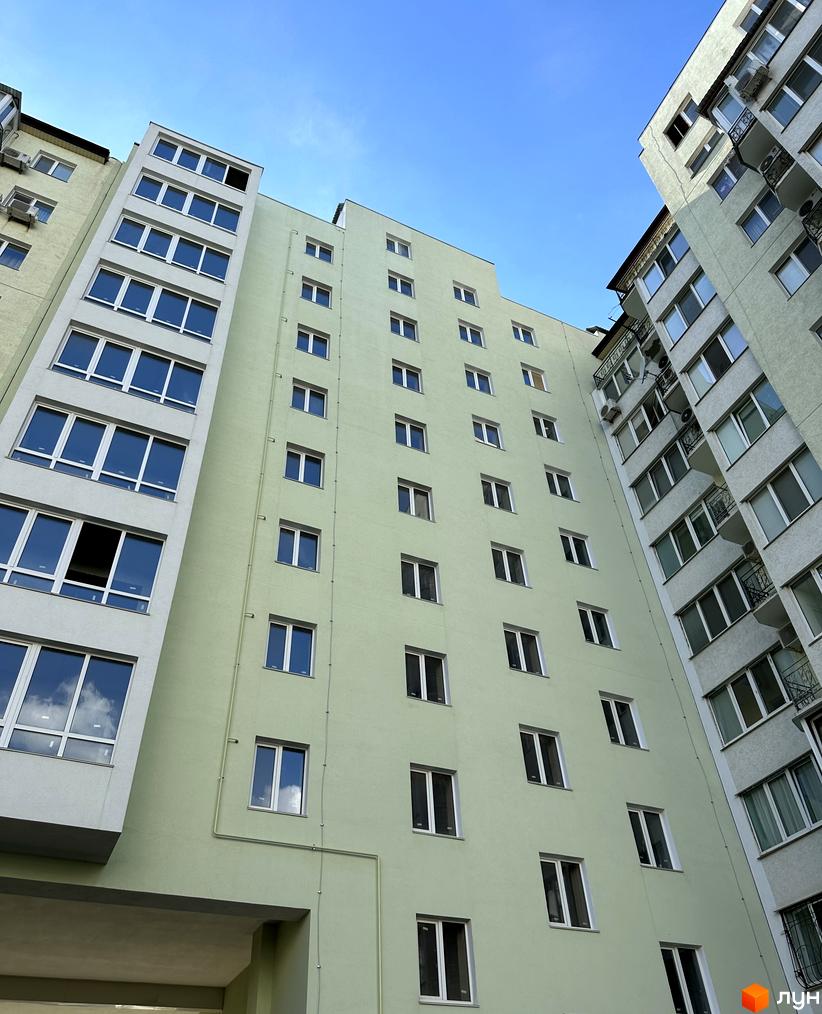 Фасад житлового комплексу Потьомкінський під блакитним небом. Багатоповерхові будинки з великою кількістю вікон та балконів.