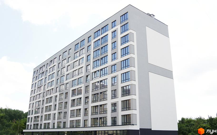 Зовнішній вигляд новобудови ЖК Молодіжний з численними вікнами та сірими фасадами. Навколо будівлі видно зелені дерева та ясне небо.