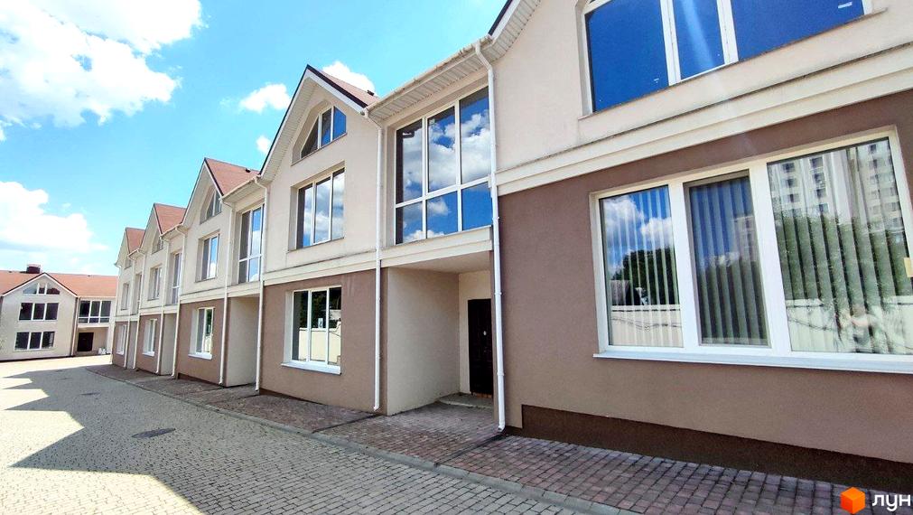 Котеджне містечко КМ На Вишневій. Зовнішній вигляд двоповерхових будинків з великими вікнами та коричневими фасадами, вимощена бруківкою прибудинкова територія.