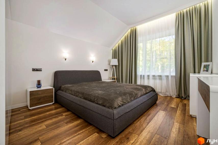 Спальня в новобудові КМ Парк хаус. Ліжко з сірим узголів'ям, дерев'яна підлога та велике вікно з сірими шторами.