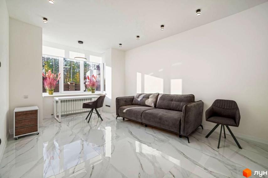 Інтер'єр вітальні у житловому комплексі КМ Парк хаус з диваном, кріслом та великим вікном. Сучасний дизайн та світлі тони.