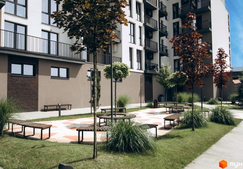 Житловий комплекс Sky Towers з білою фасадною частиною та балконами, прибудинкова територія з ландшафтним дизайном та місцями для відпочинку.