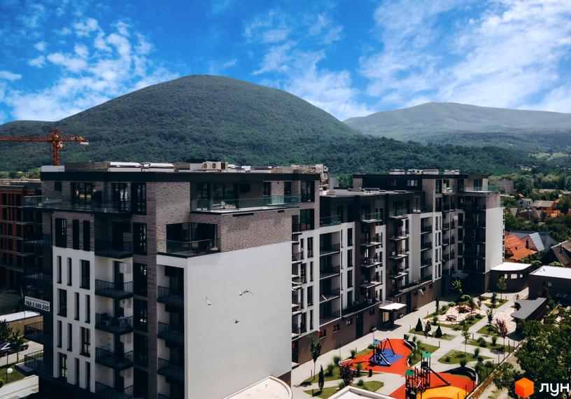 Житловий комплекс Sky Towers з фасадами з цегли та білої штукатурки, балконами зі скляним огородженням та дитячим майданчиком.