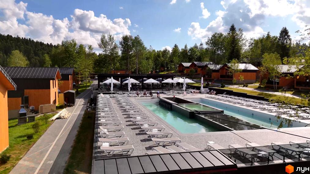 Котеджне містечко PHOENIX MEDICAL RESORT з басейном та шезлонгами. Навколо зелені дерева та хмарне небо.