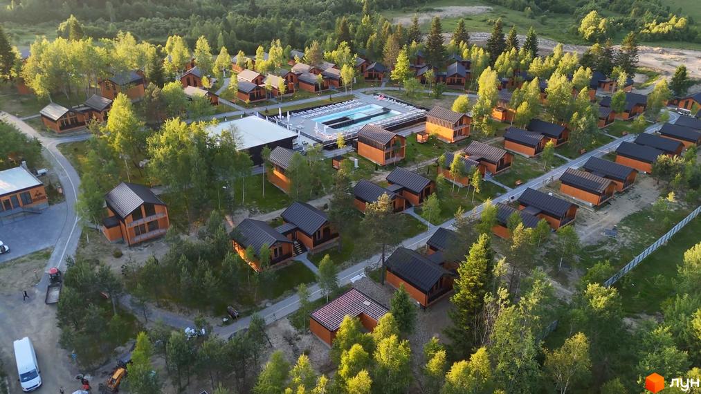 Котеджне містечко PHOENIX MEDICAL RESORT з дерев'яними будинками та басейном, оточене зеленню та деревами. Територія комплексу доглянута, з доріжками та зонами відпочинку.