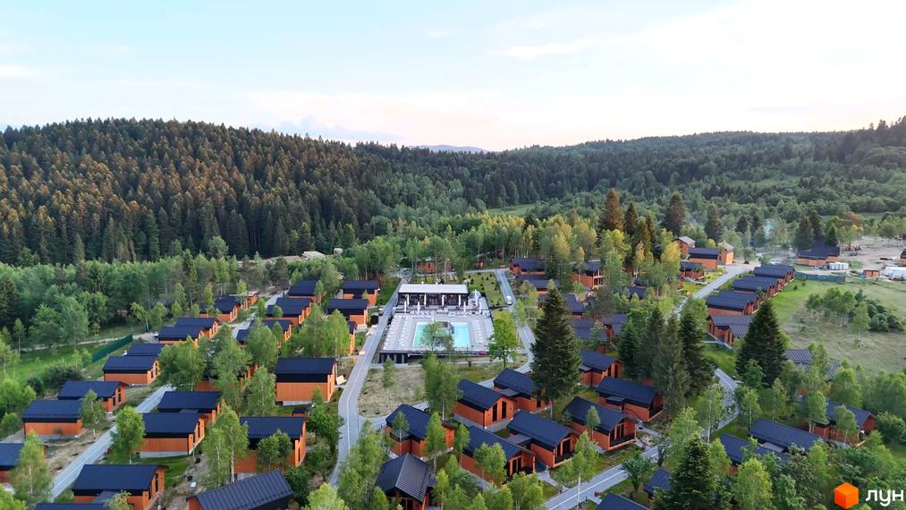 Котеджне містечко PHOENIX MEDICAL RESORT з дерев'яними будинками та чорними дахами, розташоване серед лісу біля басейну та зони відпочинку.