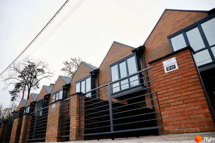 Вигляд будинків Котеджного містечка Positano Park з цегли з великими вікнами та чорною огорожею.