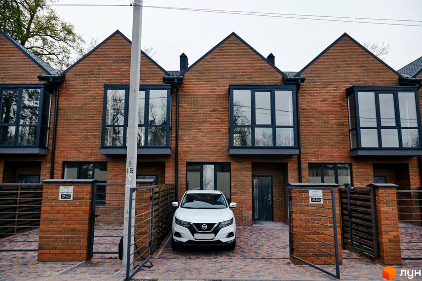 Вигляд таунхаусів з червоної цегли в Котеджному містечку Positano Park. Перед будинками акуратний двір, викладений бруківкою.