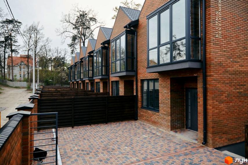 Зображення Котеджного містечка Positano Park: ряд цегляних будинків з великими вікнами та доглянутою прибудинковою територією.