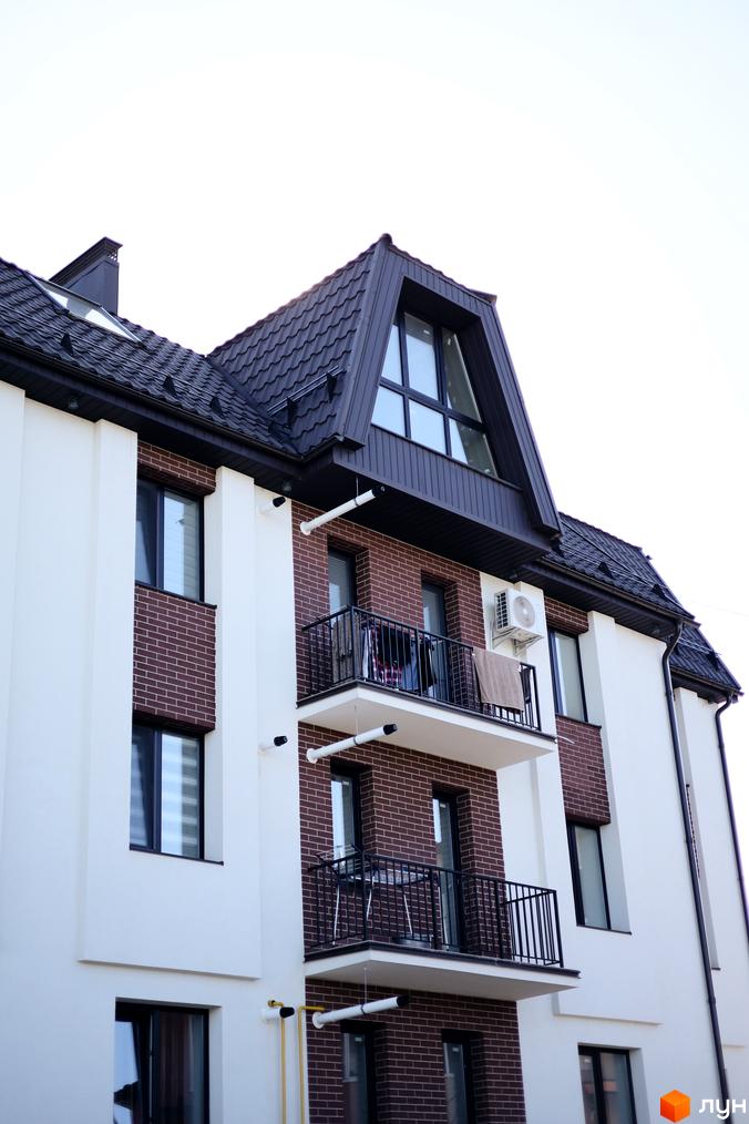 Зовнішній вигляд житлового комплексу Comfort House з цегляними фасадами та балконами. Новобудова має багатоповерхові секції та мансардний поверх.