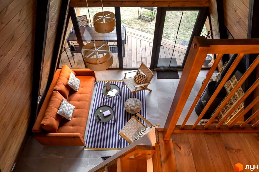 Інтер'єр вітальні комплексу відпочинку УЛІС з помаранчевим диваном, килимом та дерев'яними елементами.