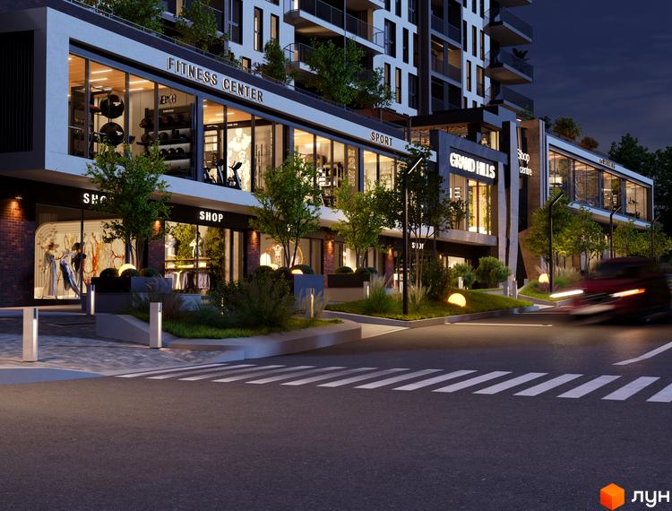 Зовнішній вигляд житлового комплексу Grand Hills з фасадами магазинів та фітнес-центром. Прибудинкова територія з освітленням та зеленню.