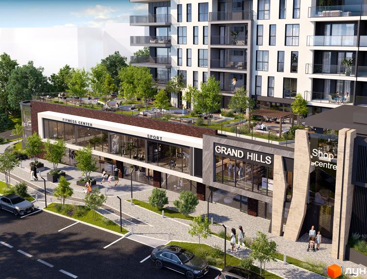 Новобудова Grand Hills з фасадом з цегли та скляними елементами. Територія комплексу озеленена, з зонами відпочинку та комерційними приміщеннями на першому поверсі.