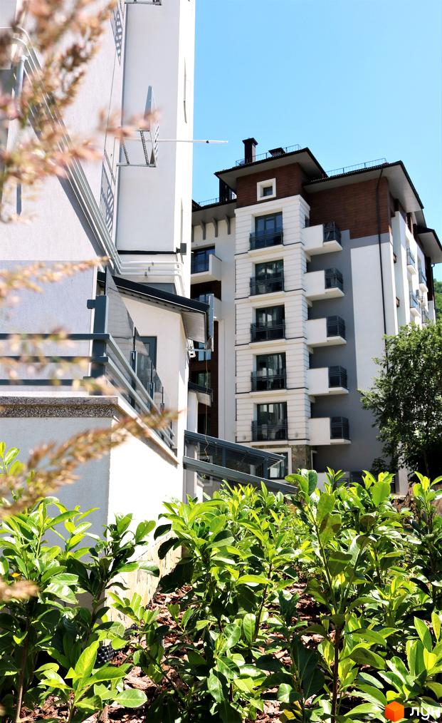 Житловий комплекс Крайобраз: фасади будівель з балконами та вікнами, зелені насадження біля будинку.