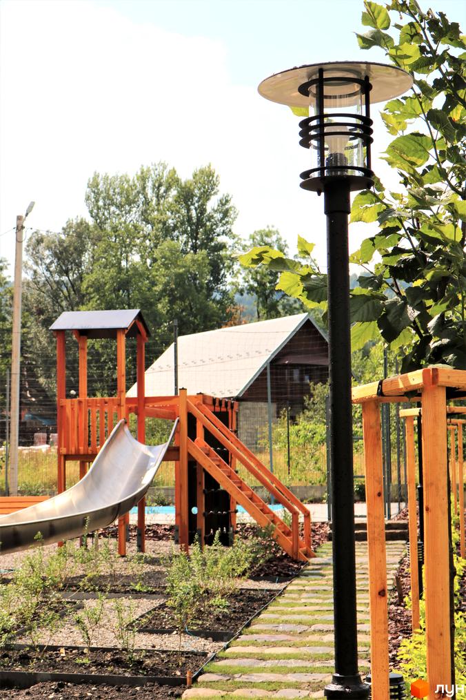Дитячий майданчик з гіркою та сходами в житловому комплексі Крайобраз. Сучасне освітлення та зелені насадження на території.