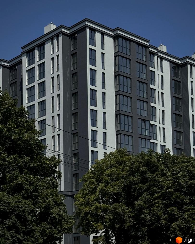 Зображення фасаду багатоповерхового будинку в Житловому комплексі Джем Сіті. Навколо будинку зелені дерева.