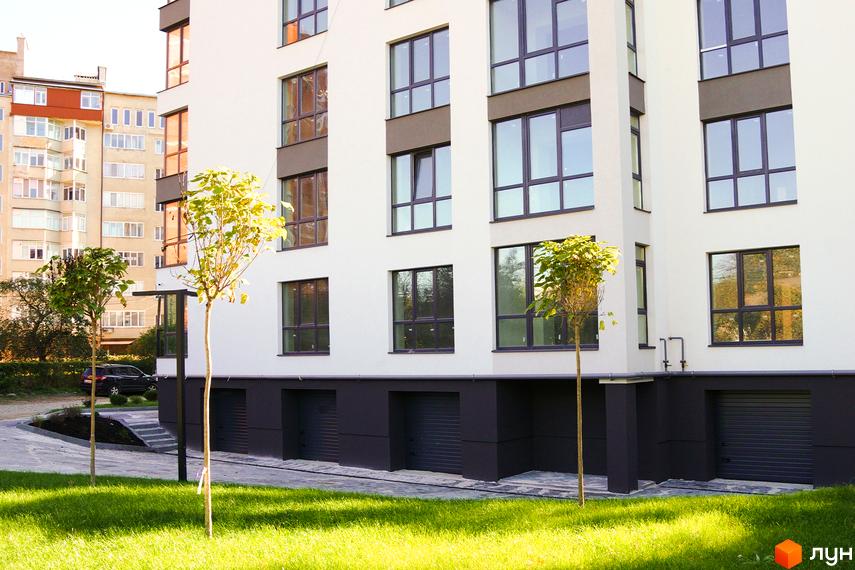 Білосніжний багатоповерховий будинок ЖК Затишний з великими вікнами та зеленими газонами на прибудинковій території.