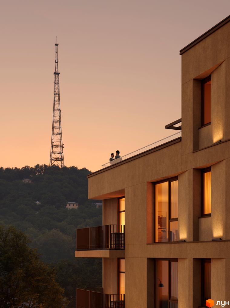 Житловий комплекс Avalon Yard Club з балконами та вікнами, що виходять на зелений пагорб з вежею на заході сонця.