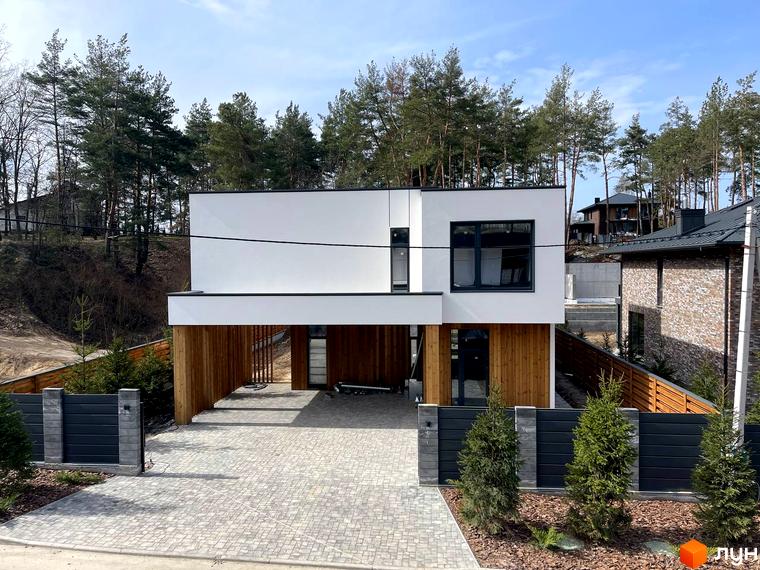 Сучасний котеджне містечко КМ Нова Ходосівка Premium з білим фасадом та дерев'яними елементами. Прибудинкова територія з бруківкою та огорожею.