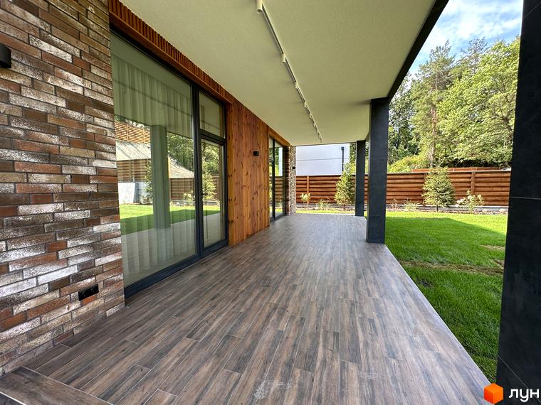 Котеджне містечко Нова Ходосівка Premium: фасад будинку з цегли та дерева, тераса з дерев'яною підлогою, зелений газон та паркан.