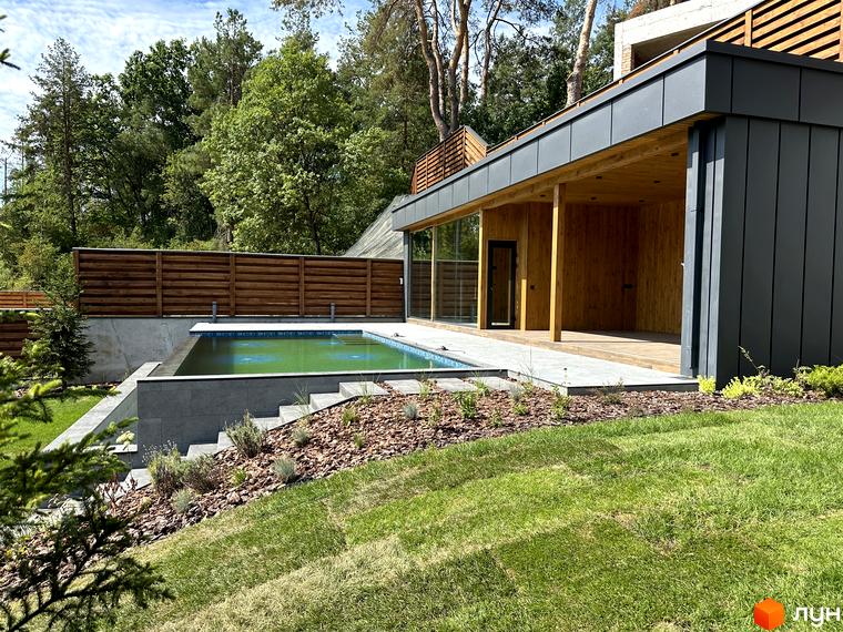 Котеджне містечко Нова Ходосівка Premium: зовнішній вигляд будинку з басейном та зеленою прибудинковою територією.